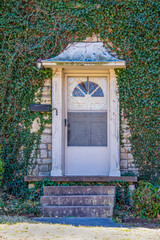 Front door with metal awning - old and worn but beautiful - set in ivy covered rock house - Close-up of entrance