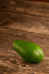 Shiny green avocado on wood