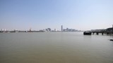 shanghai bund viewed from Xuhui Bingjiang Park, skyscrapers with blue sky background, cargo ships sailing on Huangpu river, 4K video, slow motion.
