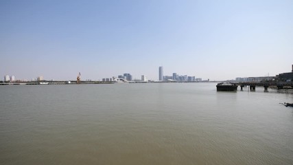 shanghai bund viewed from Xuhui Bingjiang Park, skyscrapers with blue sky background, cargo ships sailing on Huangpu river, 4K video, slow motion.