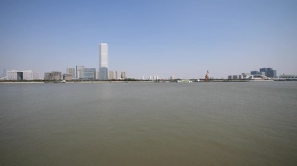 shanghai bund viewed from Xuhui Bingjiang Park, skyscrapers with blue sky background, cargo ships sailing on Huangpu river, 4K video, slow motion.