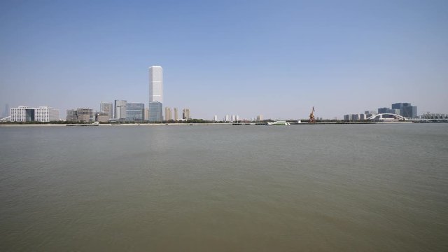 shanghai bund viewed from Xuhui Bingjiang Park, skyscrapers with blue sky background, cargo ships sailing on Huangpu river, 4K video, slow motion.