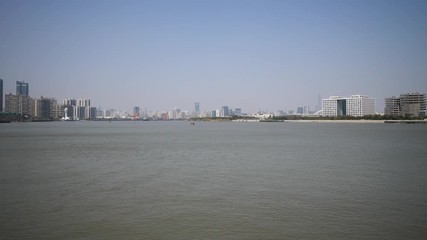 shanghai bund viewed from Xuhui Bingjiang Park, skyscrapers with blue sky background, cargo ships sailing on Huangpu river, 4K video, slow motion.