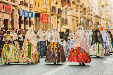 Several of the thousands of women Falleras who parade down the street of La Paz with their typical Valencian Spanish dresses during the offering of Fallas to the Virgin, seen from behind.