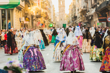 Several of the thousands of women Falleras who parade down the street of La Paz with their typical Valencian Spanish dresses during the offering of Fallas to the Virgin, seen from behind. - obrazy, fototapety, plakaty