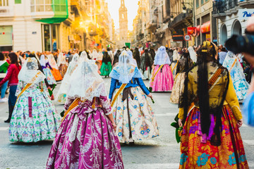 Fototapeta na wymiar Several of the thousands of women Falleras who parade down the street of La Paz with their typical Valencian Spanish dresses during the offering of Fallas to the Virgin, seen from behind.