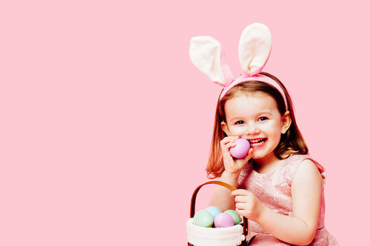Portrait of a happy little toddler girl with easter bunny ears and a basket of eggs