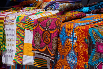 Colorful and vibrant cloth and fabric with dynamic patterns displayed on a street market table.