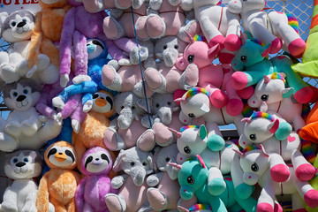 Stuffed animal toys at a fair as prizes hanging on mass on a wall.