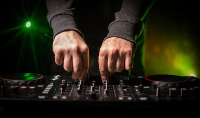 DJ Spinning, Mixing, and Scratching in a Night Club, Hands of dj tweak various track controls on...