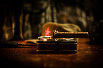 Close up of a Cuban cigar and ashtray on the wooden table. Communist dictator commander table in...