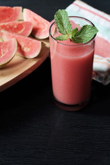 Glass of guava smoothie and slice of its fruit