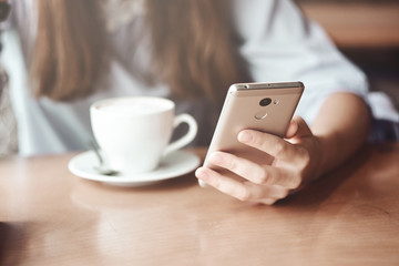 Business woman hands using smart phone and cup of coffee.