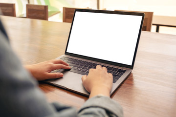 Mockup image of a woman using and typing on laptop with blank white desktop screen on wooden table in office