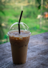 Iced coffee drink on wooden table against green nature background