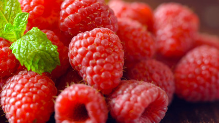 Macro closeup of summer fruit raspberries on wooden table.