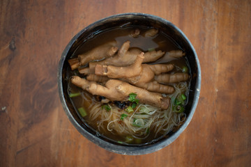 Thai chicken feet soup with noodle served in a thai coconut bowl.