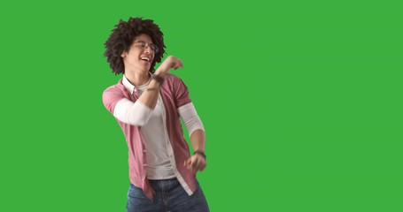 Happy young man with curly hair dancing over green background