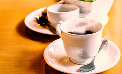 Hot coffee in white mug on wooden table in coffee shop in the morning