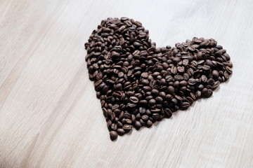 Heart shape arranged by coffee beans and wood pattern as background