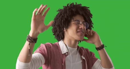 Happy man dancing while listening music on earphones over green chroma key background