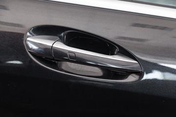 View on closed black front door with handle with keyless access made from chromium of luxury car after detailing and polishing