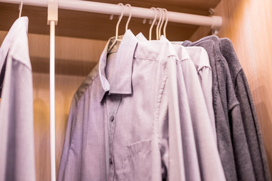 Many shirts hanging on a rack.Row of men's suits hanging in closet. concept of buy and sell, business man.Man's closet. Hangers with shirts closeup. Male wardrobe.Wardrobe rack with men's clothes