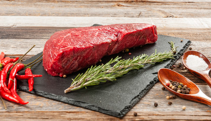Raw meat, beef with spices for cooking on black board