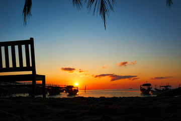 Bench with beautiful sunrise in background on tropical beach Koh rong Landscape with longtail boats while sun is going up