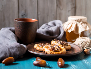 Romantic morning still life, in a rustic style with cookies, a glass jar of honey and scattered dates on a turquoise wooden background