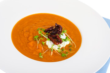 Carrot pumpkin cream soup in white plate.