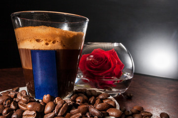 Chocolate drink in glass near red rose