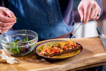 Chef decorates the vegan sandwiches with baked vegetables and cheese on fried craft bread. Master class in the kitchen. The process of cooking. Step by step. Tutorial. Close-up