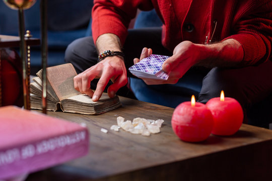 Inspired fortune-teller using old little magic book while reading cards