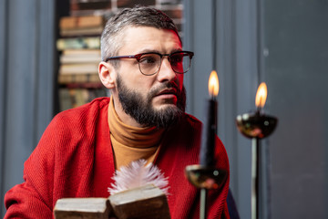 Bearded diviner feeling thoughtful after reading ancient magician book