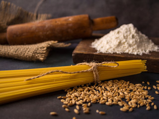 Italian pasta, spaghetti, wheat, rolling pin, flour on a textured background. Still life in a rustic style. Element for design