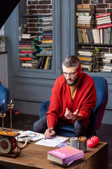 Astrologist sitting at the table with candles studying new practice