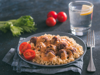 Bulgur dish idea and recipe. Bulgur with homemade roasted beef meatballs on dark blue background. Copy space for text