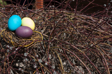 Dyed eggs in a nest on willow branches.