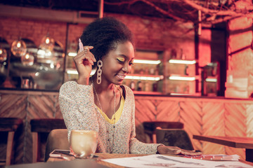 Beaming appealing dark-haired African designer doing fashion drawings in cafeteria