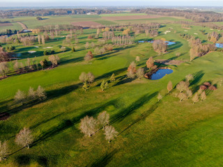 Fototapeta premium Aerial view of a golf course. Beautiful colorful trees and green course during autumn/winter season in the South of Belgium, Walloon Brabant.