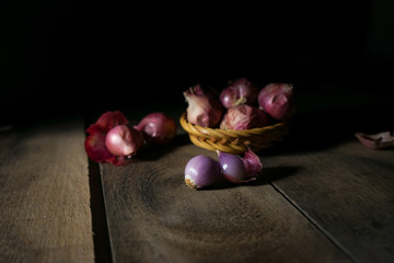 red garlic in wooden basket with black background.