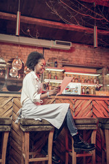 Alluring barmaid checking menu while having seat at bar chair