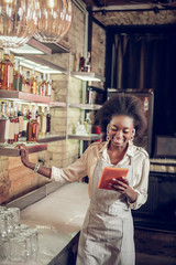 Smiling African-American bartender reading new cocktail recipe at loft bar