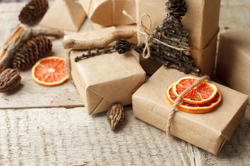 Rustic gift wrapped in craft paper with natural decoration on wooden table with pine cones. Simple eco presents plastic free. Zero waste christmas concept