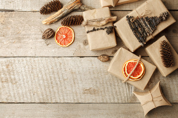 Rustic gift wrapped in craft paper with natural decoration on wooden table with pine cones. Simple eco presents plastic free. Zero waste christmas concept, copy space