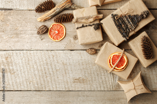 Rustic gift wrapped in craft paper with natural decoration on wooden table with pine cones. Simple eco presents plastic free. Zero waste christmas concept, copy space