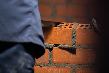 Closeup hand professional construction worker laying bricks in new industrial site