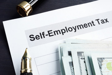 Self employment tax form and money with calculator.