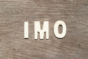 Alphabet letter in word IMO (Abbreviation of in my opinion) on wood background